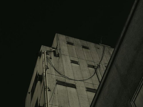 見上げるビルの外壁と配管