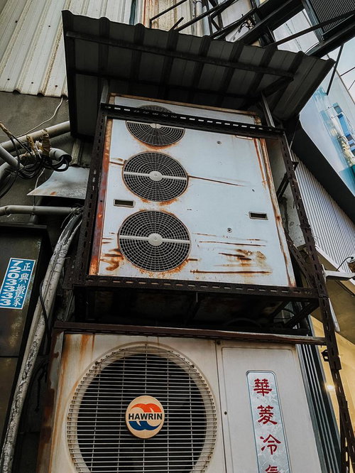 老朽化したビルの壁に設置された複数の業務用エアコン室外機