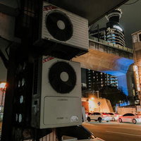 古びたエアコン室外機が並ぶ雑然とした夜間のビル裏路地の写真