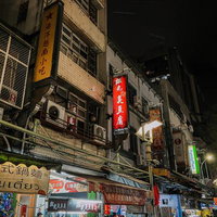 ネオンが灯る台湾の屋台街の路地裏、漢字看板と夜市の賑わいの写真