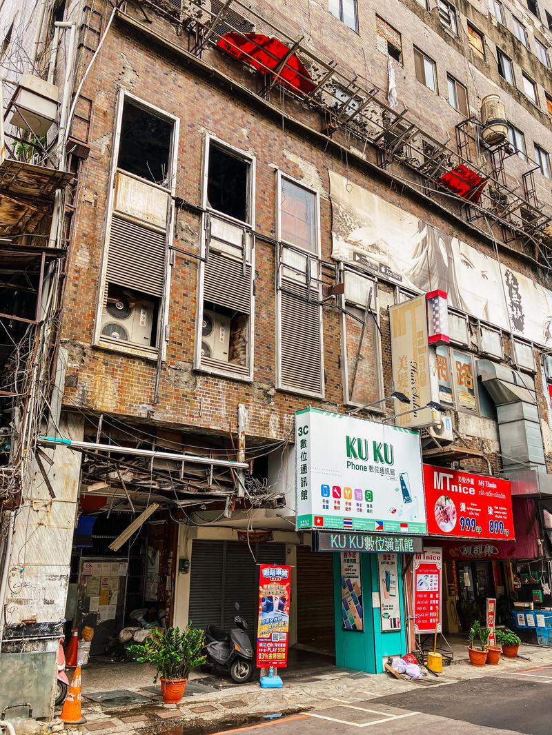台湾の街角にある老朽化した赤レンガの雑居ビルと路面店