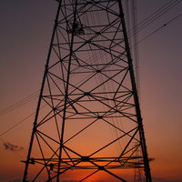夕焼け空に浮かぶ鉄塔と送電線のシルエットの写真