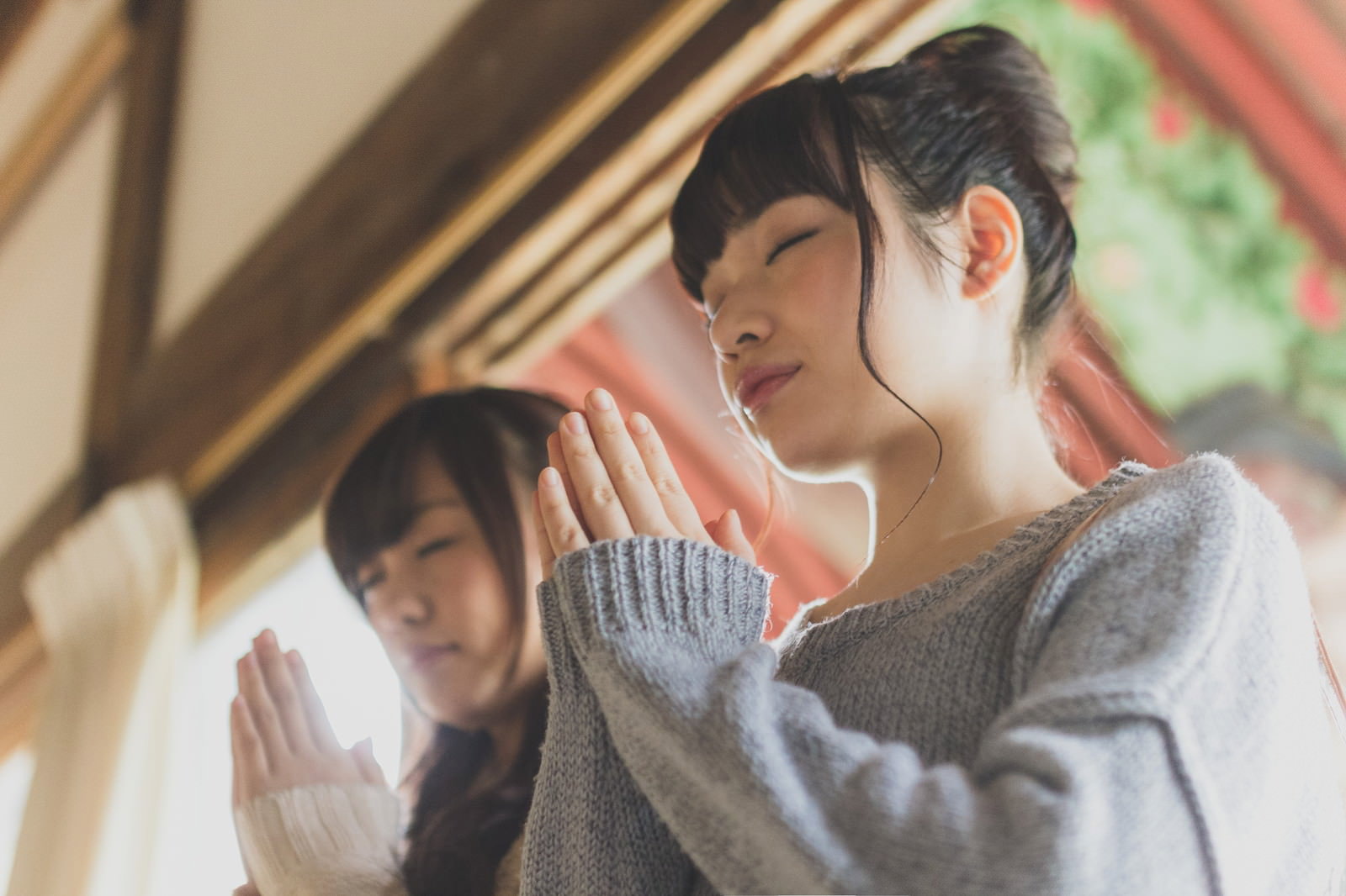 寺院の室内で手を合わせて祈る女性たち［モデル：河村友歌 渡辺友美子］