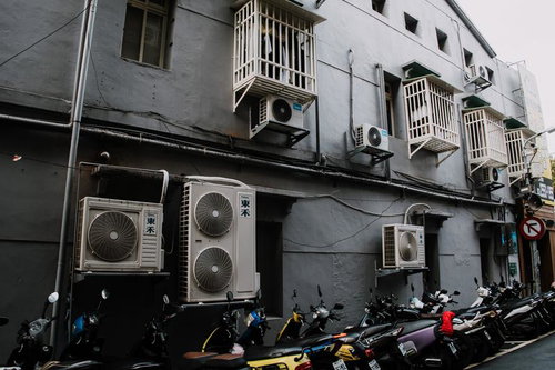 バイクと複数のエアコン室外機が並ぶ台湾の路地裏