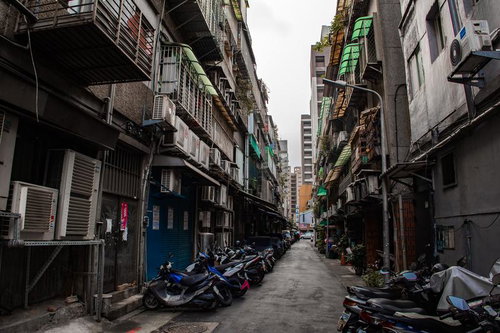台湾の路地裏に並ぶバイクと古い建物、室外機と看板