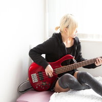 ベッドの上でレッドベースを練習するベーシストの写真