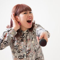 客を煽るマイクを握る女性ボーカルのステージパフォーマンスの写真