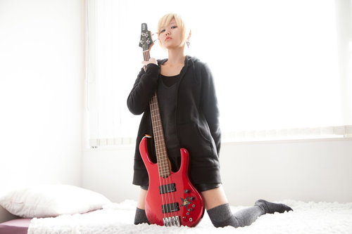 やってみた系の動画にチャレンジしようか迷っている赤いベースを持つ女性ベーシストの写真