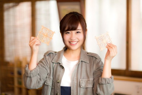 おみやげに招き猫を手に持ってガッツポーズする女性