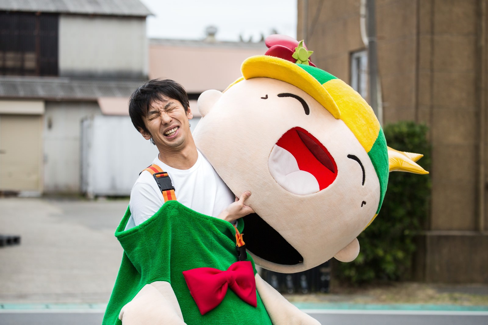ゆるキャラを抱えて疲れた顔をする男性［モデル：ホットくん 大川竜弥］