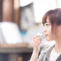 蔵元で日本酒をいただく若い女性観光客、おちょこを手にした試飲風景の写真