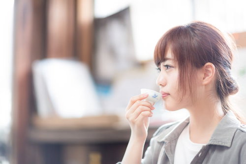 蔵元で日本酒をいただく若い女性観光客、おちょこを手にした試飲風景