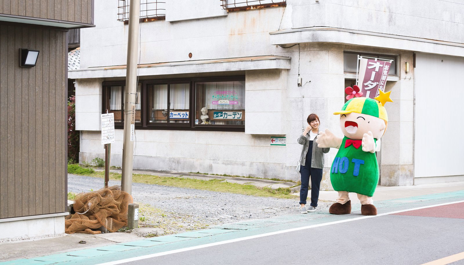 大原中央商店街でHOTくんと女性が並ぶ［モデル：ホットくん 河村友歌］