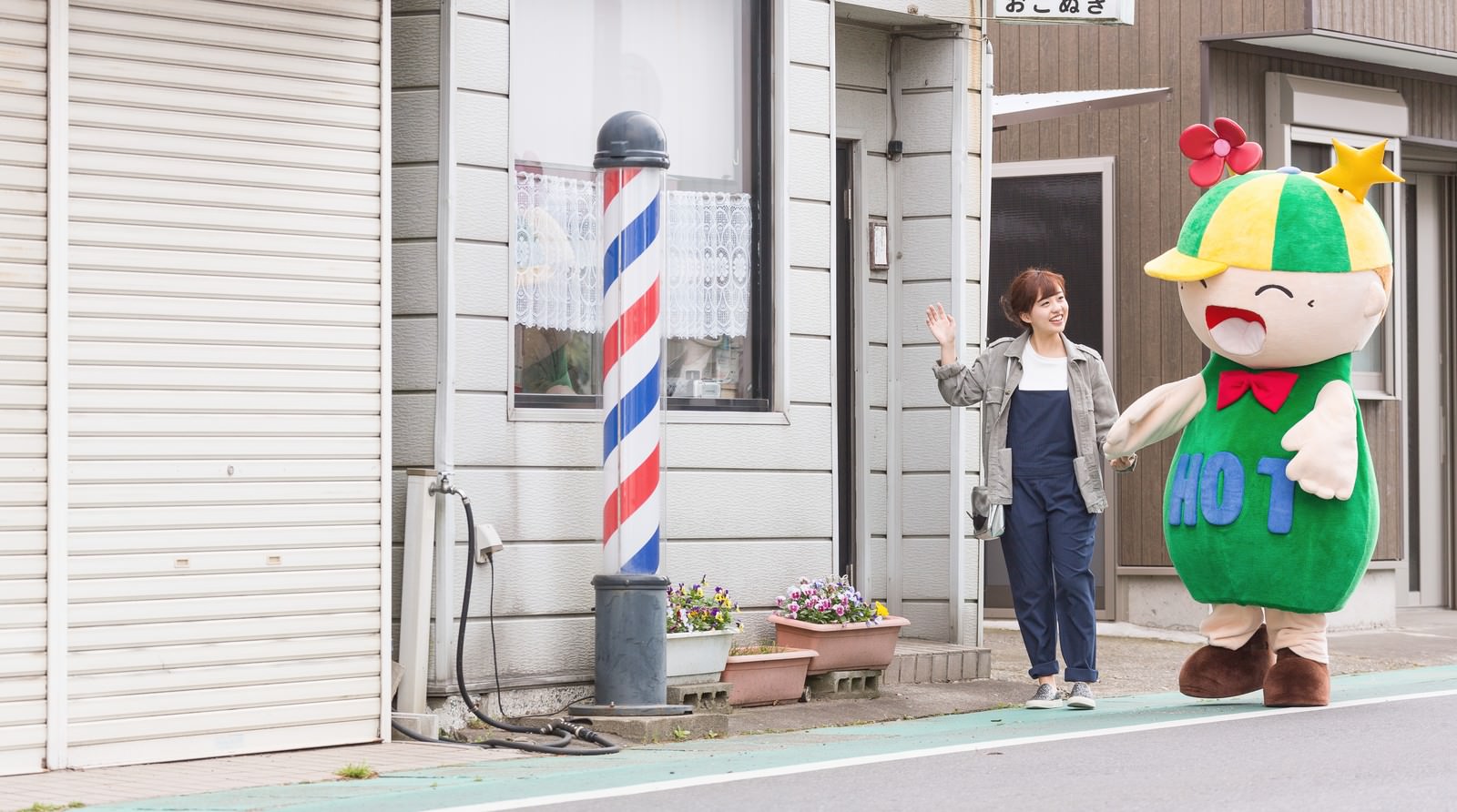 大原中央商店街の理髪店前でゆるキャラと並ぶ看板娘［モデル：ホットくん 河村友歌］