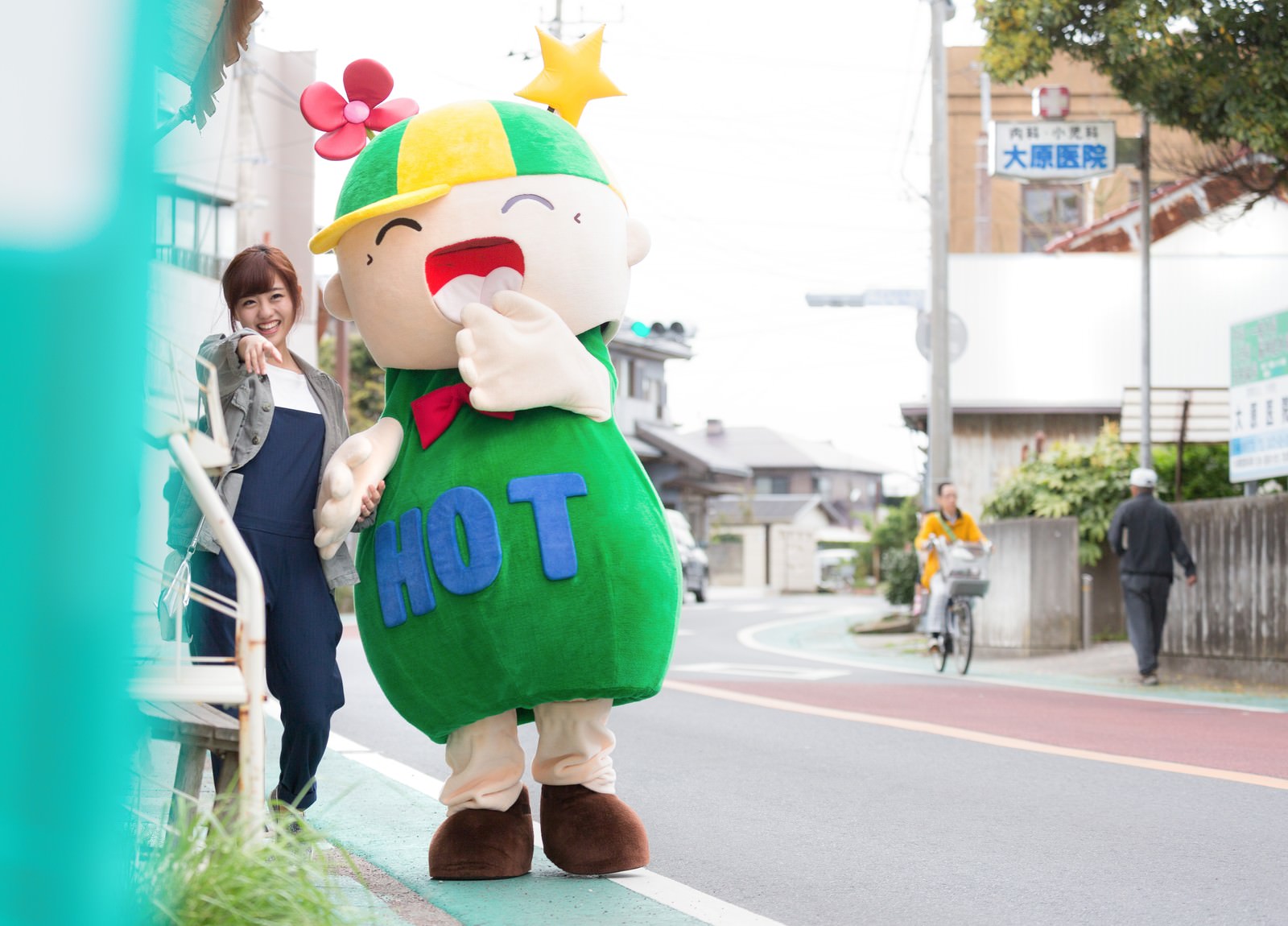 大原中央商店街でゆるキャラと並んで笑顔の女性［モデル：ホットくん 河村友歌］