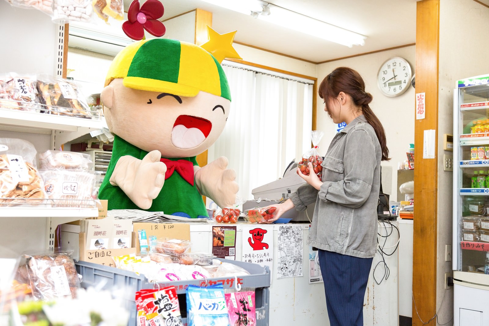 商店街でレジ打ちをするゆるキャラと女性客［モデル：ホットくん 河村友歌］