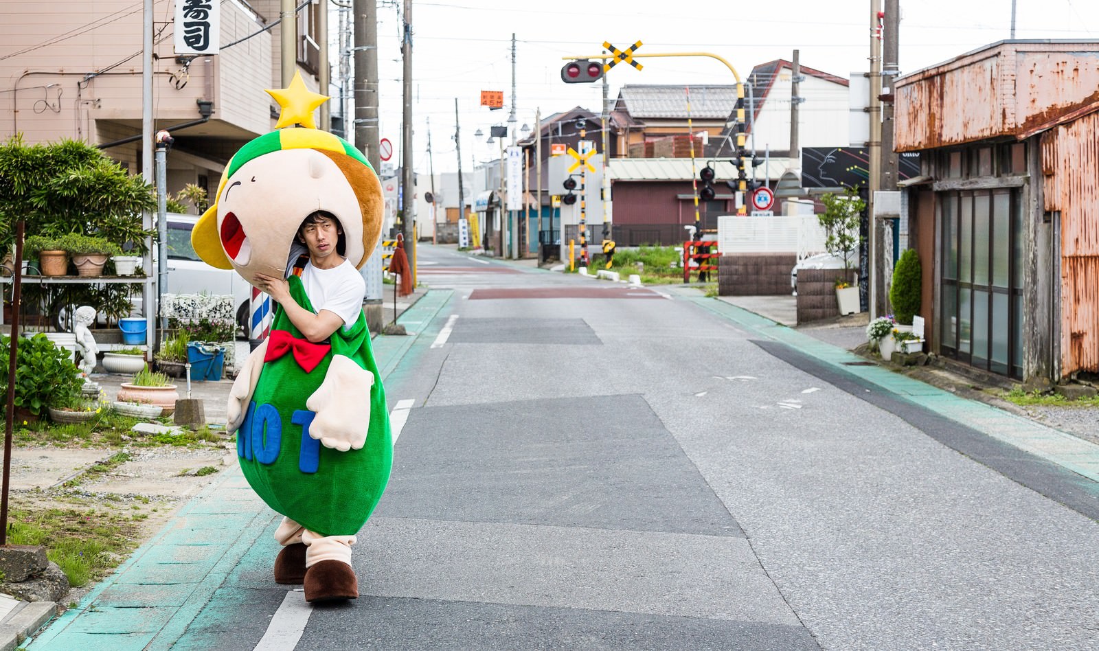 真夏の住宅街でゆるキャラの着ぐるみを着た人物［モデル：ホットくん 大川竜弥］