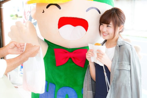 大原中央商店街で人気のコロッケを手にするゆるキャラと女性観光客