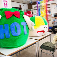 待機所のテーブルに置かれたゆるキャラと次回勤務日を確認する中の人の写真