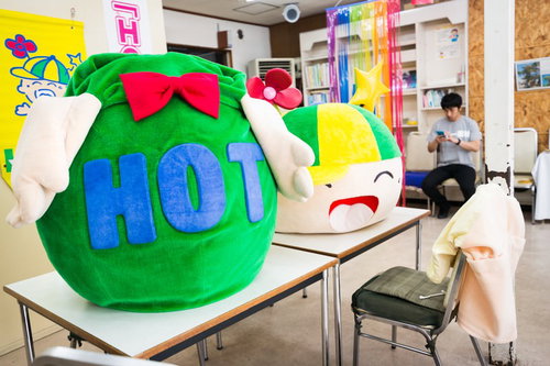 待機所のテーブルに置かれたゆるキャラと次回勤務日を確認する中の人