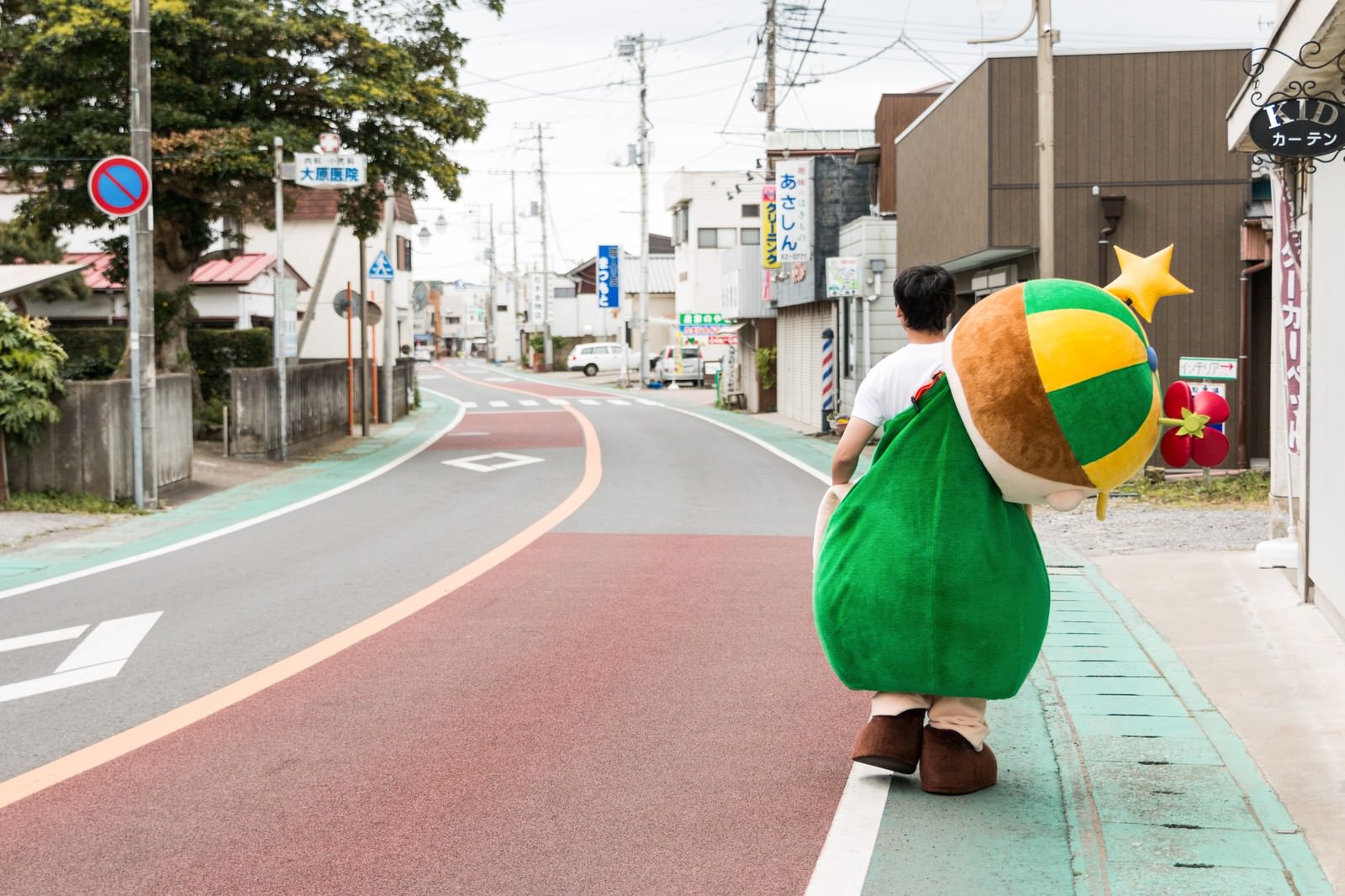 大原中央商店街の道を歩くゆるキャラの後ろ姿［モデル：大川竜弥 ホットくん］