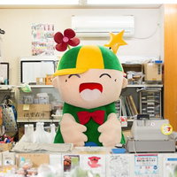 笑顔でお客様を迎えるホットくん、大原中央商店街のふれあい市場でレジ打ちの写真