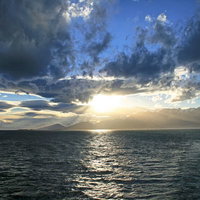 穏やかな海に昇る朝日と山々、夜明けの水平線の写真
