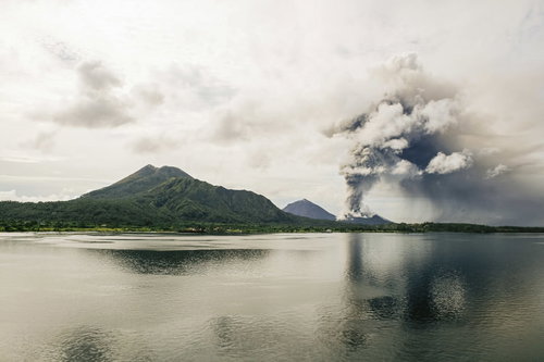 高台から見下ろす噴煙を上げる火山島と青い海