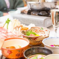 窓から自然光が差す室内テーブルに肉や野菜と鍋料理が並ぶしゃぶしゃぶの写真