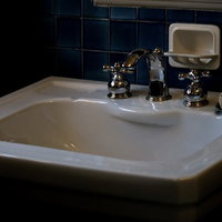 苔が生えた薄暗い手洗い場の蛇口の写真