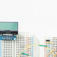 白い背景に配置した小さなモノクロ液晶とブレッドボードの写真