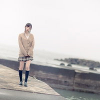 埠頭の木製甲板を歩く女子高生、カーディガンとプリーツスカートの制服姿の写真