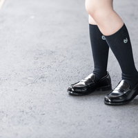 制服姿の女子高生が履くローファーと紺色ハイソックスの足元の写真