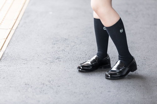 制服姿の女子高生が履くローファーと紺色ハイソックスの足元