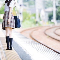 誰もいない田舎の駅のホームで振り返る女子高生の写真