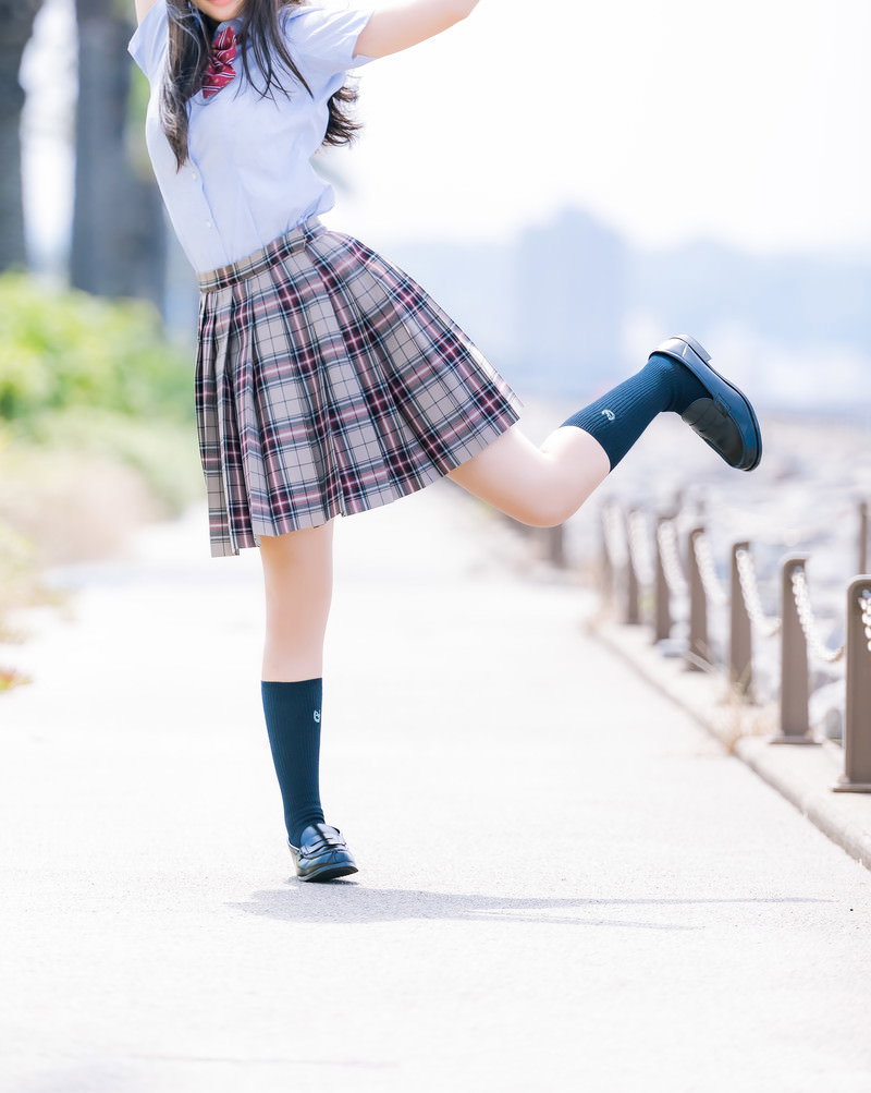 チェック柄のスカート制服を着て踊るポーズをとる女子高生［モデル：石投げて美奈代］