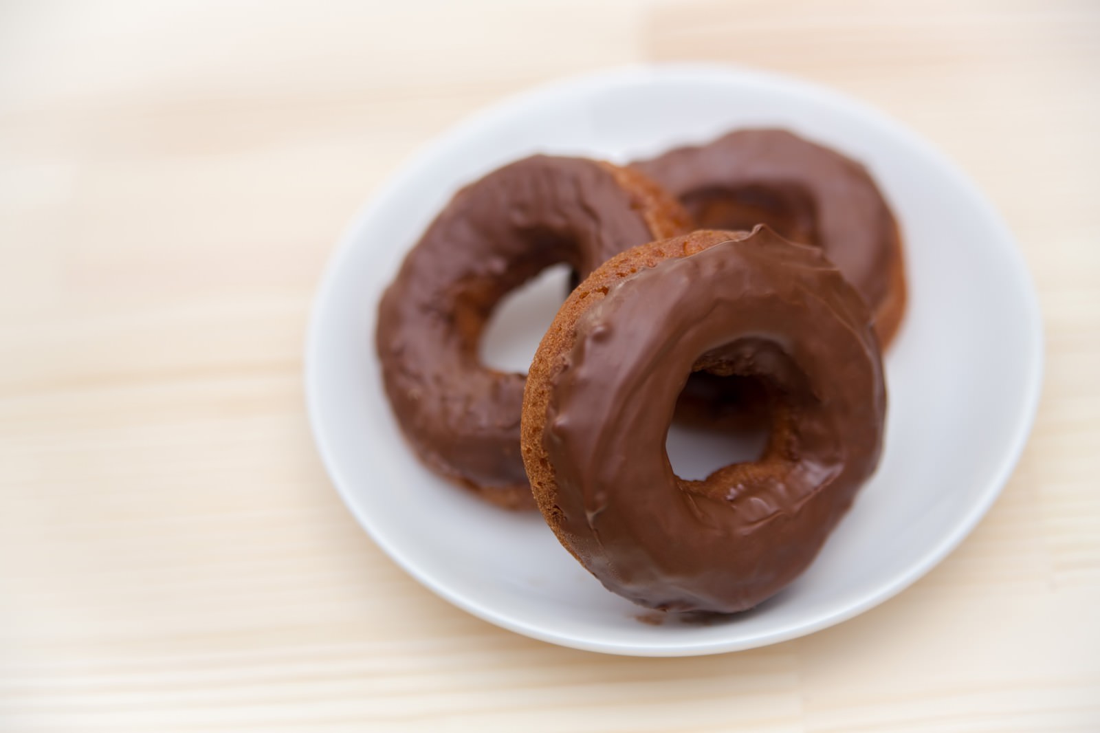 白い皿に盛られたチョコレートがけのドーナツ3個