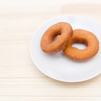 白いお皿の上に2個並んで置かれたチョコとプレーンのドーナツの写真