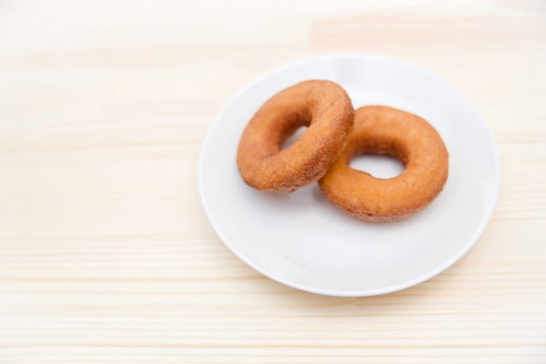 白いお皿の上に2個並んで置かれたチョコとプレーンのドーナツ