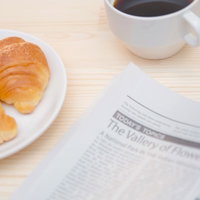 焼きたてのパンとコーヒーカップが並ぶ朝のコーヒータイムの写真