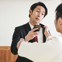 「いま撮った動画見たい？」と煽るスーツ男性の写真