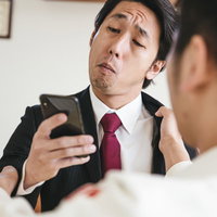 組み手中もメールチェックを欠かさないスーツ姿の男性の写真