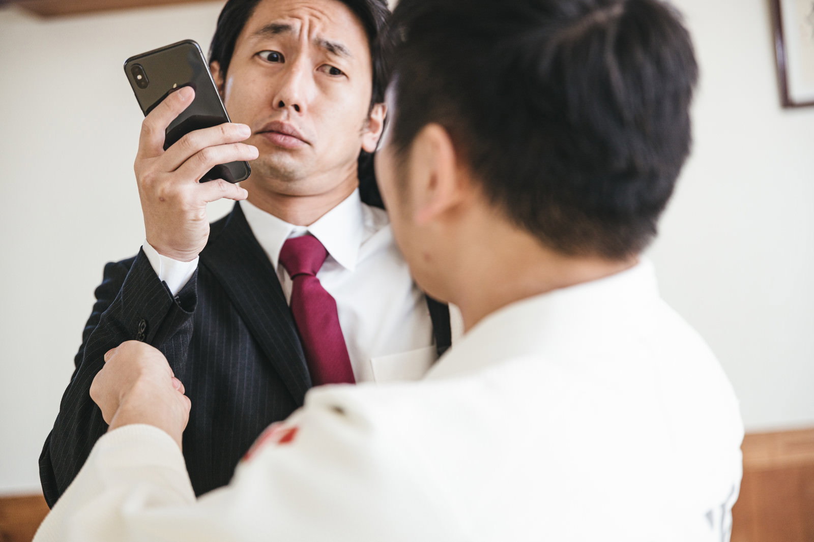 柔道着の人物に胸ぐらをつかまれるスーツの男性［モデル：大川竜弥］