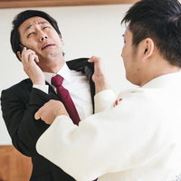 スーツのサラリーマンをぶん投げる柔道着の男性の写真