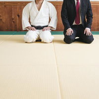 畳の上で正座する柔道着の男性とスーツ姿の男性の写真