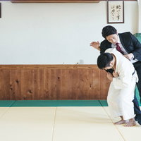 スーツ姿で一本背負いの投げ技をかけられるサラリーマンの写真