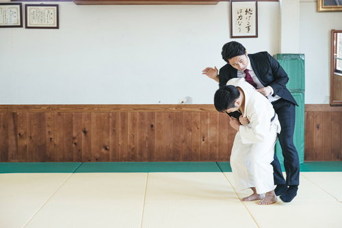 スーツ姿で一本背負いの投げ技をかけられるサラリーマン