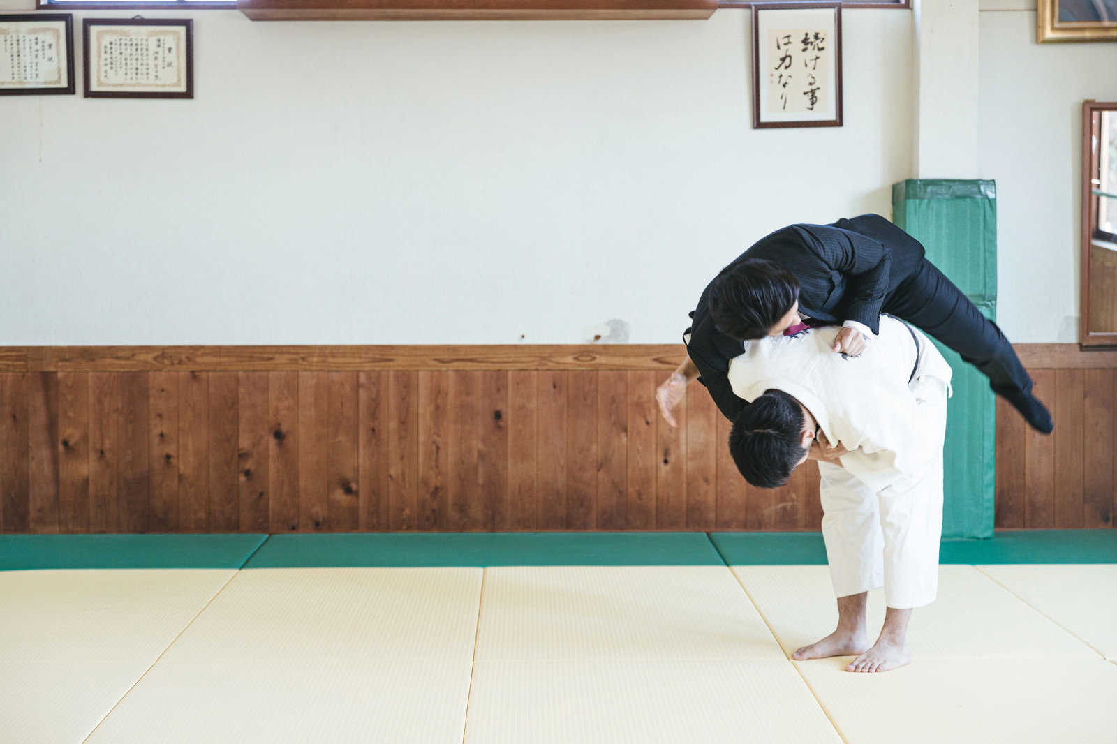 道場でスーツ姿のサラリーマンが一本背負いで投げられている［モデル：大川竜弥］
