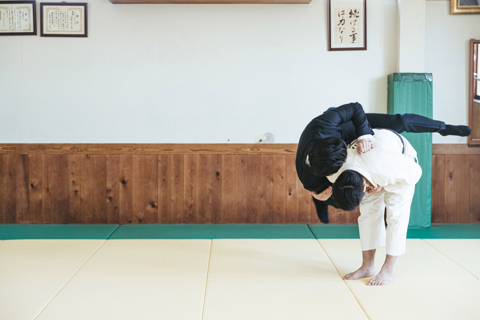 道場で一本背負いによって投げられるスーツ姿のサラリーマン［モデル：大川竜弥］