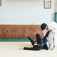 柔道の一本背負いで投げられるスーツ姿のサラリーマンの写真